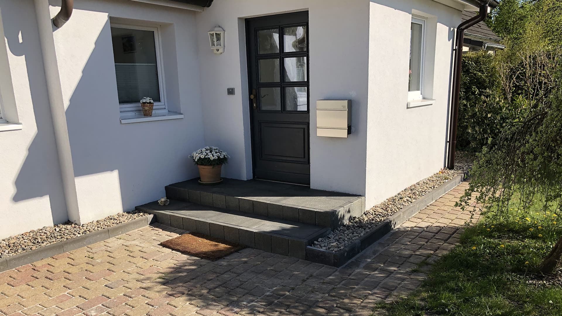 Ein weißes Haus mit kleiner Treppe zu dunkler Eingangstür